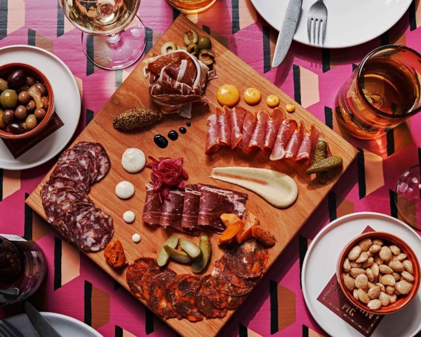 A charcuterie board at Iberian Pig in Nashville topped with slices of jamón Ibérico flanked by bowls of Marcona almonds and marinated olives.