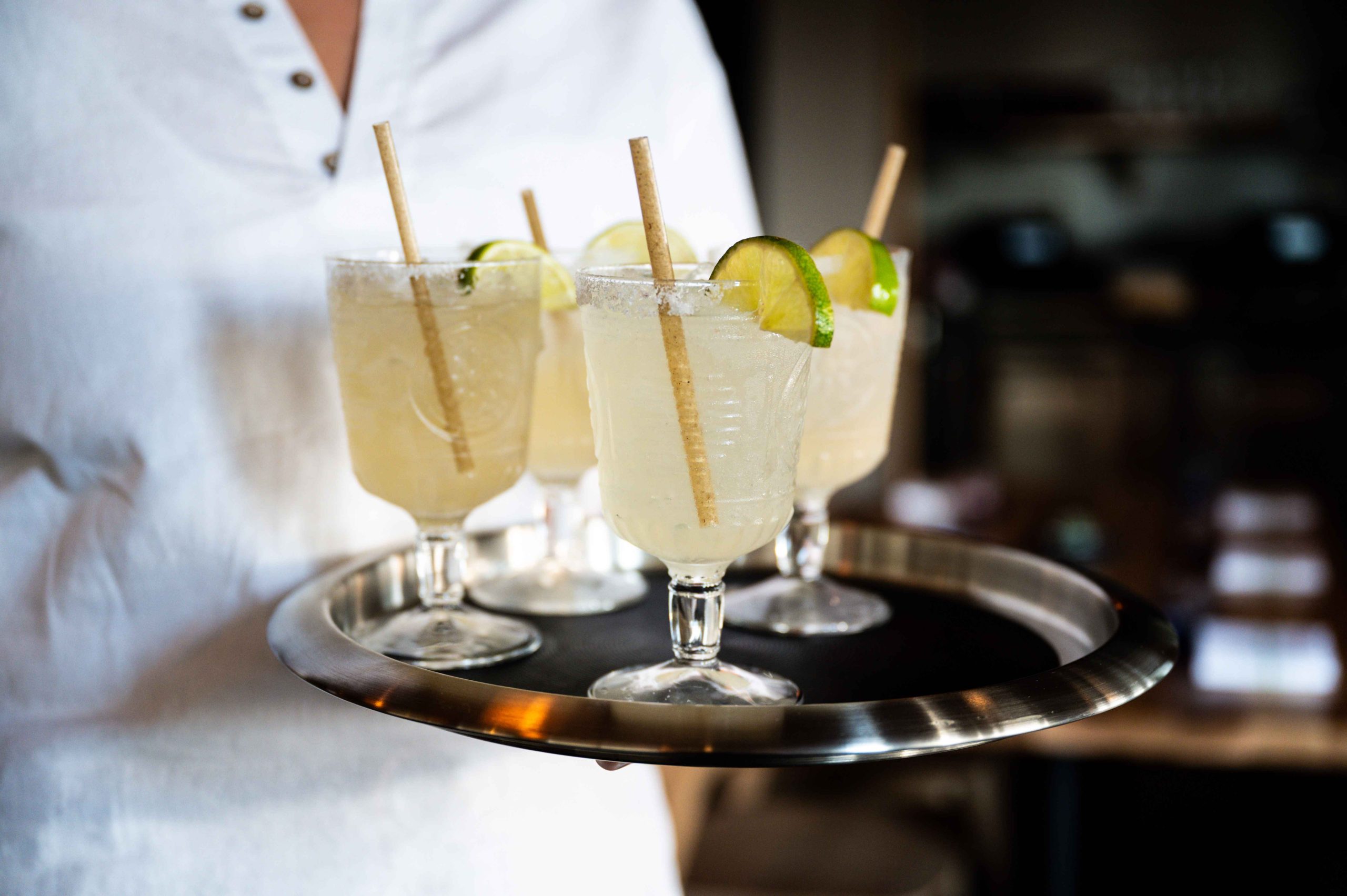A server holds a tray of margaritas with salt rims and lime garnishes at Bulevar Mexican Kitchen in Austin.