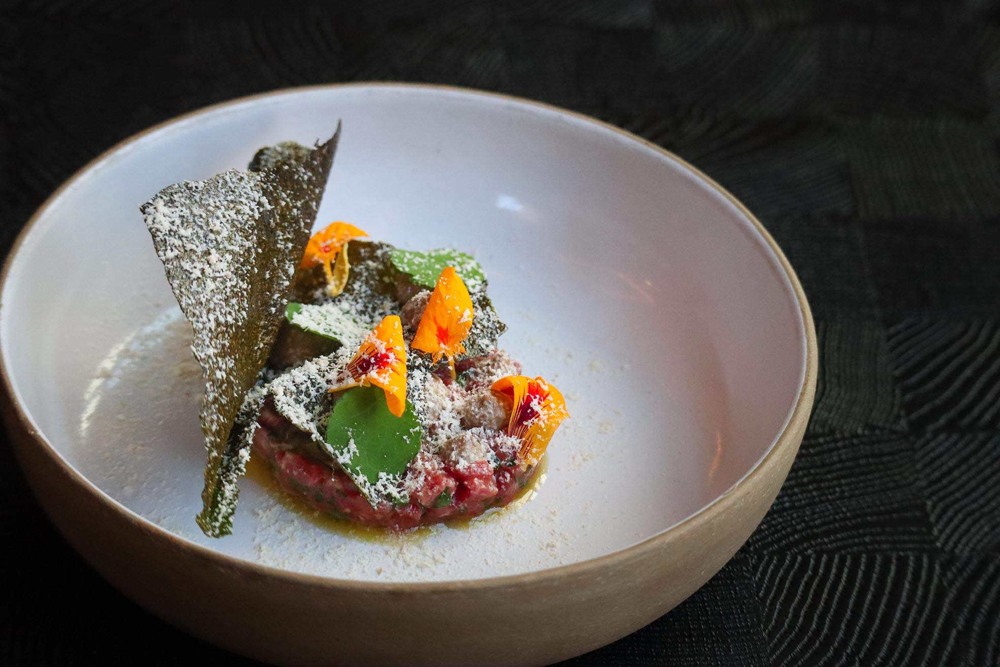 Local beef tartare topped with edible flowers at Yolan in Nashville