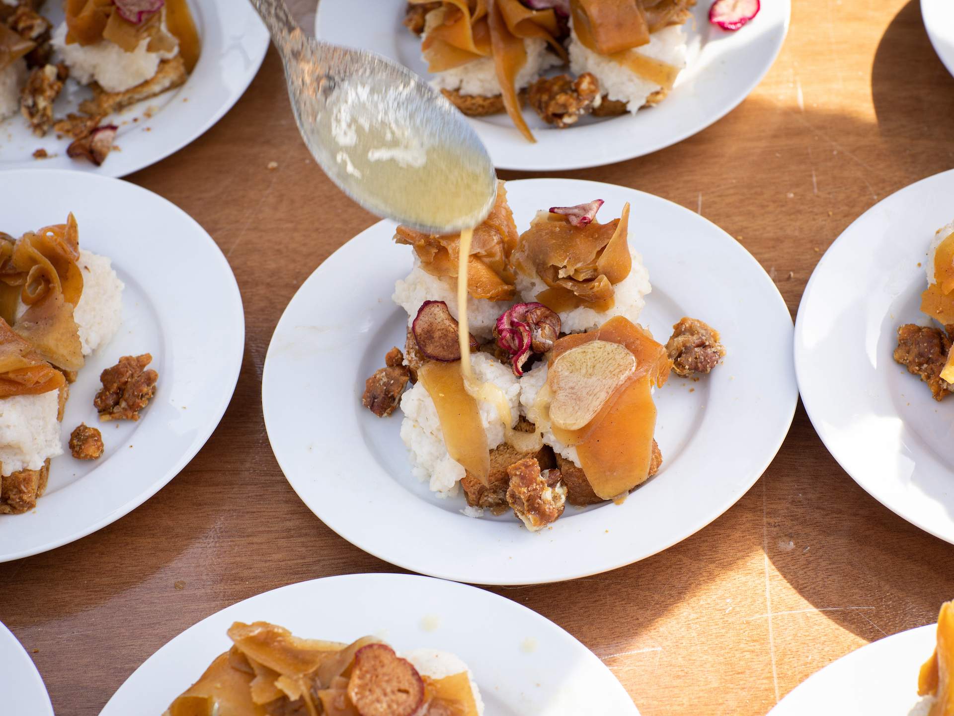 A plate of food at the BayHaven food festival with sauce being poured from a spoon on top of a plate.