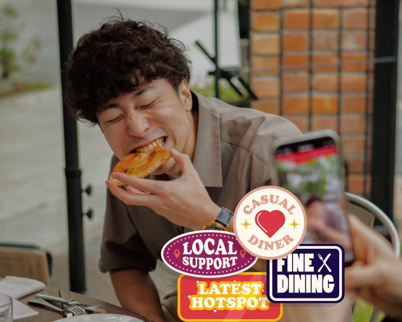 A man eats pizza while someone takes his photo