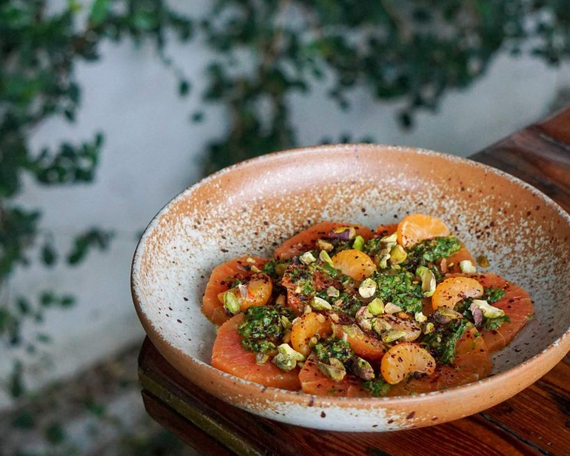 A bowl of Cara Cara orange salad topped with pistachio slivers at Manuela in Los Angeles