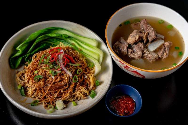 A plate of wheat stick noodles and a bowl of braised meat at Kebaya in NYC