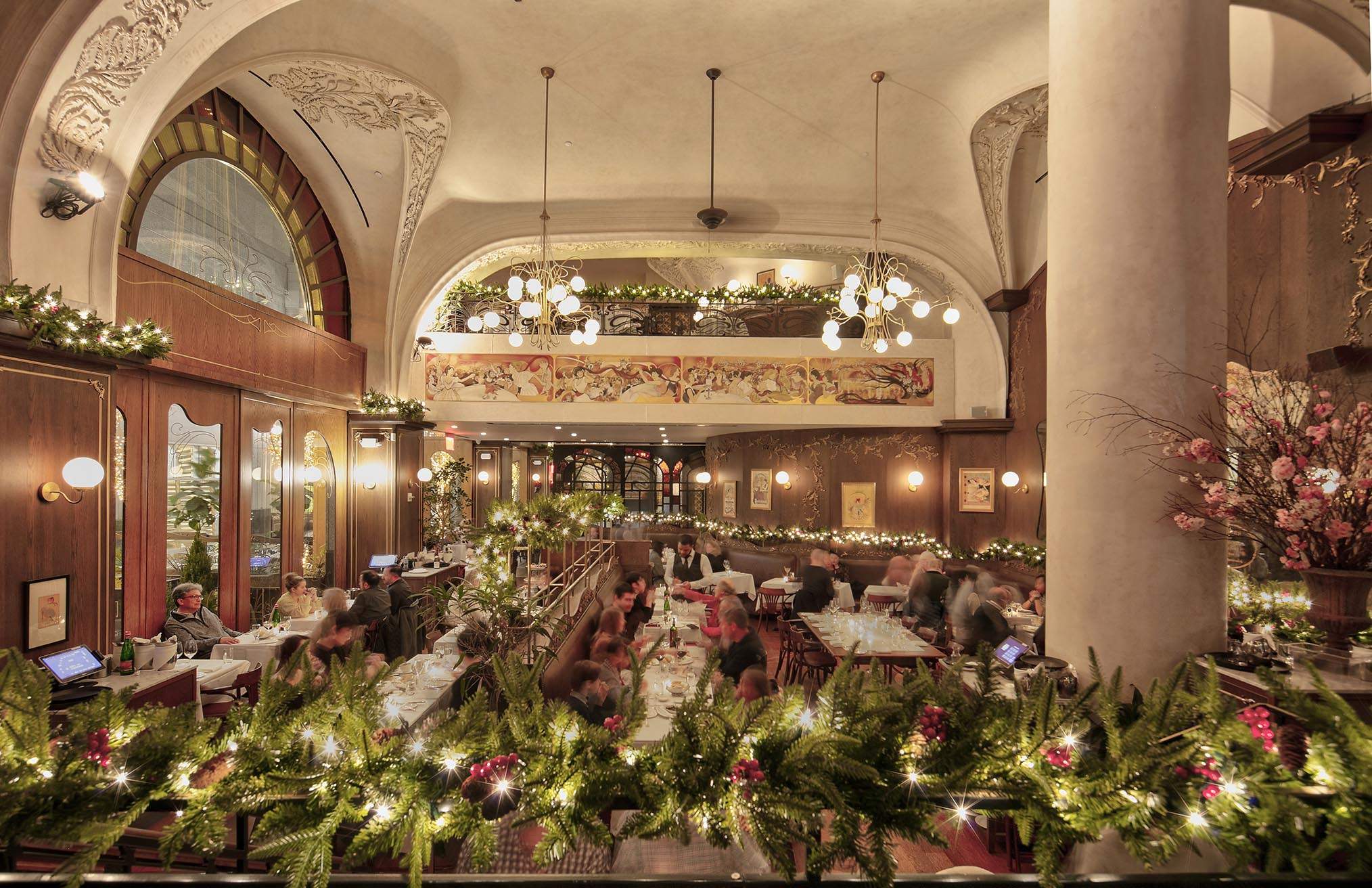 Christmas decor, featuring green garlands and twinkling lights at La Grande Boucherie, a brasserie in Midtown West.