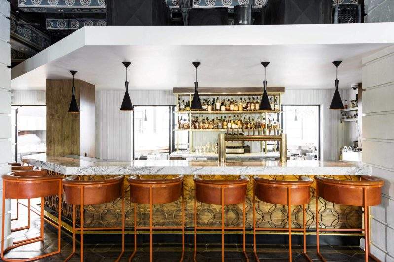 The marble-topped bar and orange leather stools at Redbird in Los Angeles