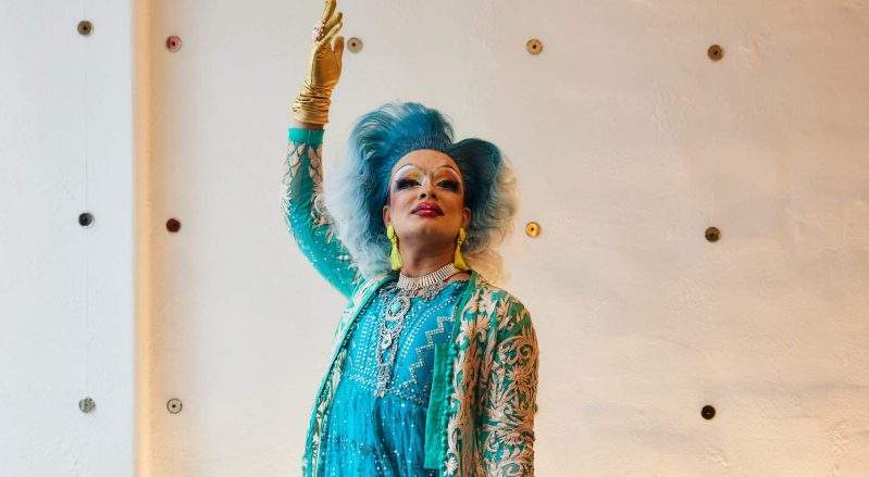 Drag queen Malai raises a gloved hand and strikes a pose at Sona in NYC.
