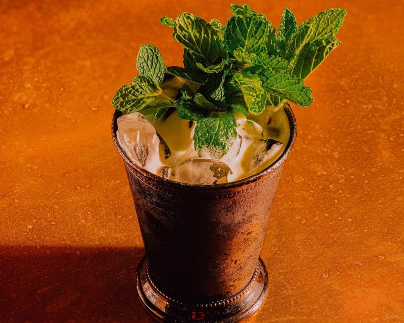 A drink in a pewter cup garnished with mint leaves