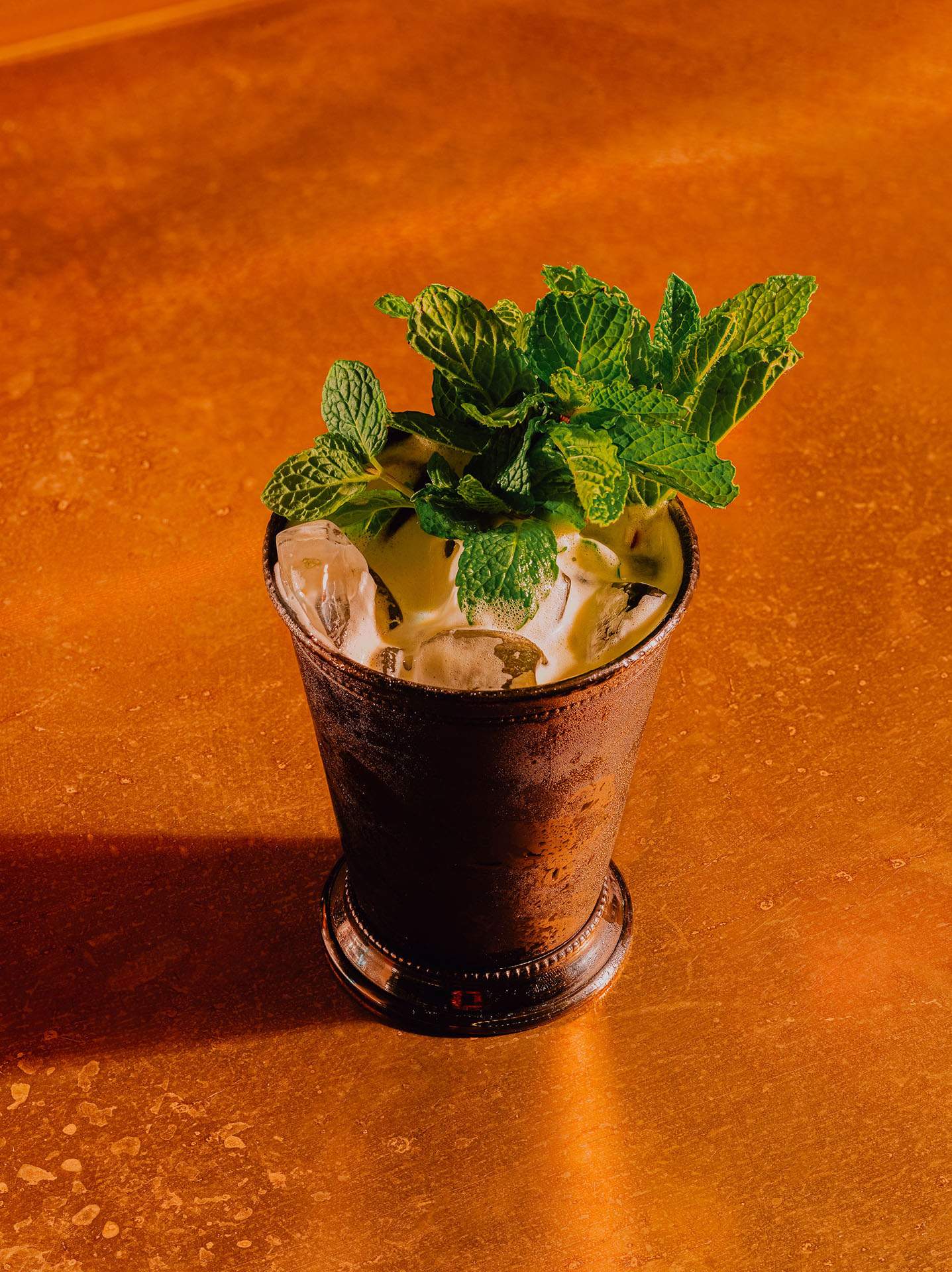 A drink in a pewter cup garnished with mint leaves