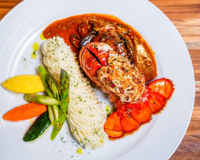 A lobster tail on a pool of sauce at the NYC restaurant Bamboo Walk
