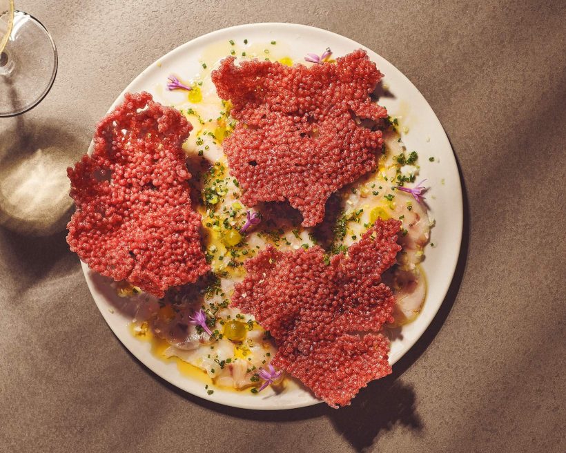A fish carpaccio dish with red crackers on top at Chicago restaurant Nisos