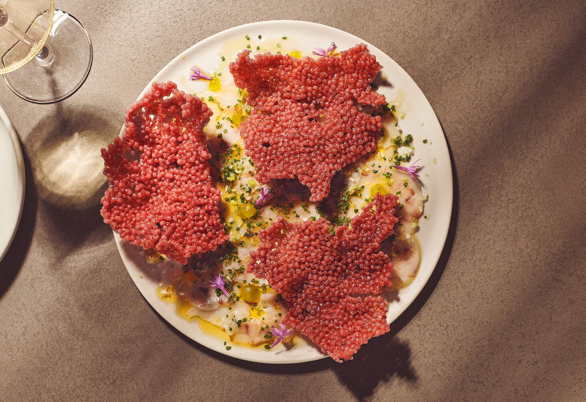 A fish carpaccio dish with red crackers on top at Chicago restaurant Nisos
