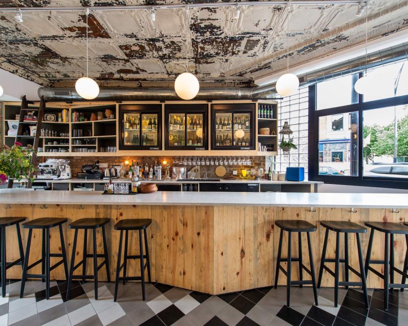 The bar area of the Chicago restaurant Wherewithall with a white marble countertop and high stools placed against it.