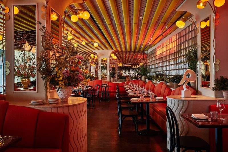 Orange banquettes and hanging plants dress the 250-seat dining room at Bad Roman in New York City.