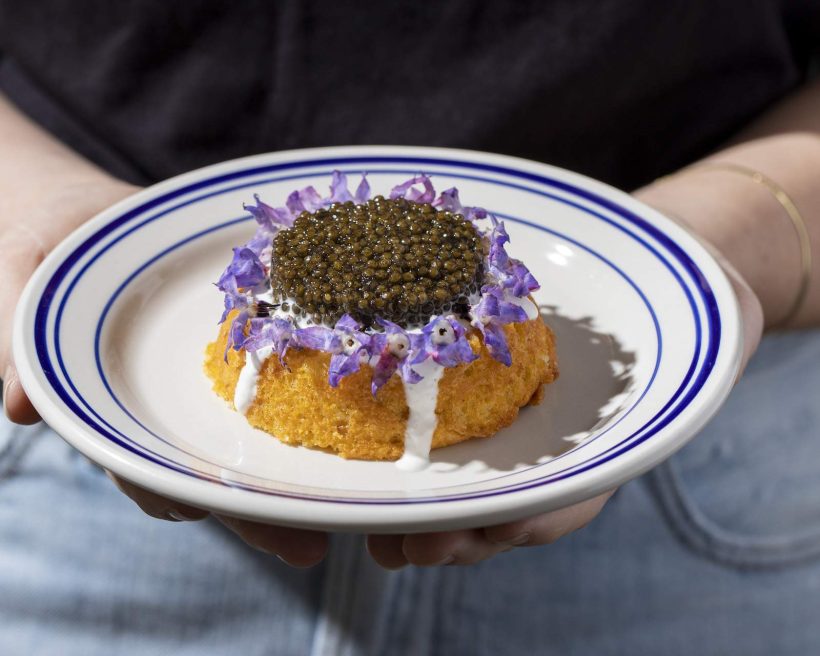 A polenta cake topped with crème fraîche, purple edible flowers, and black caviar at Los Angeles Italian restaurant Jemma di Mare