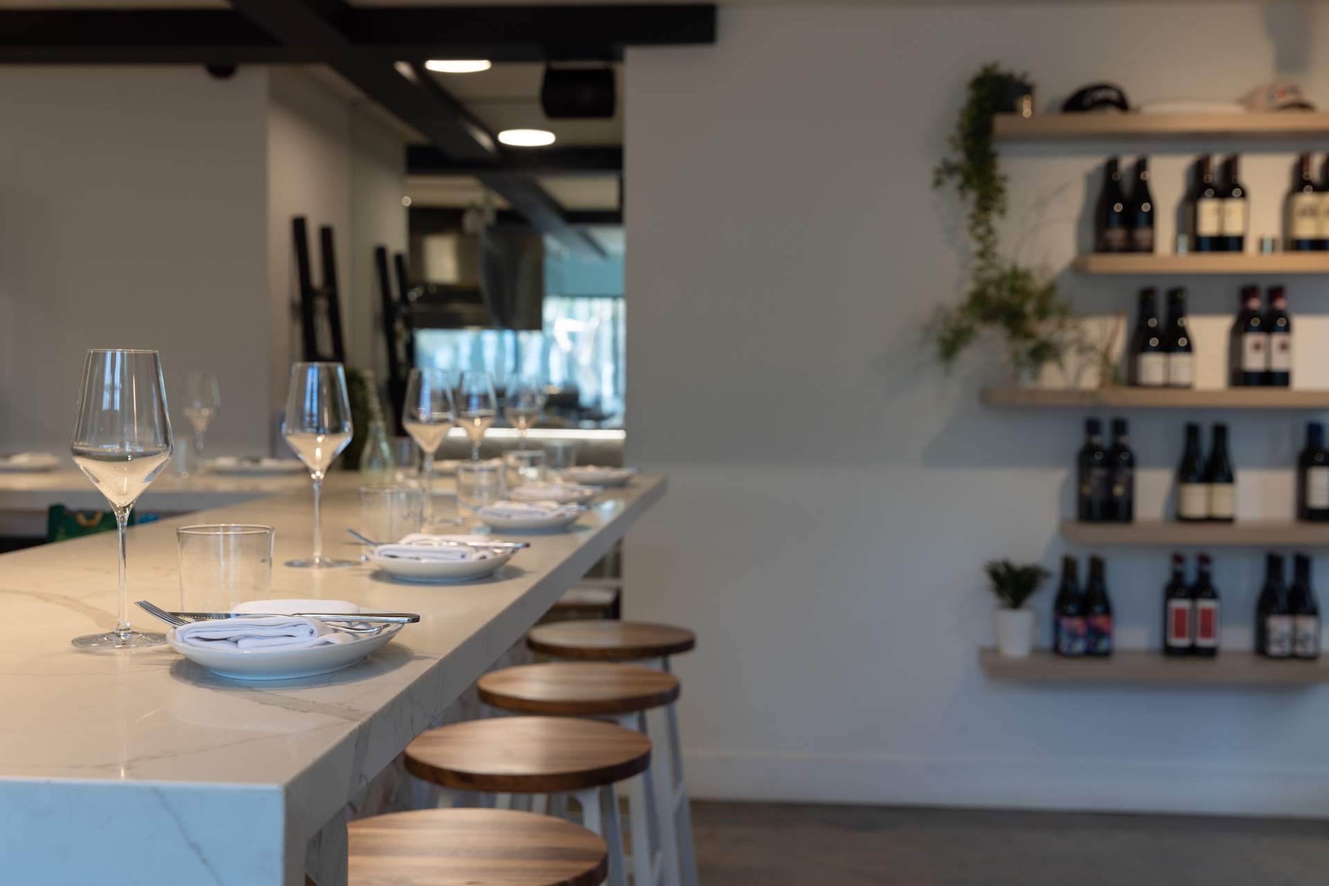 The interior of the LA pasta restaurant Cento with a white marble counter and wooden stools