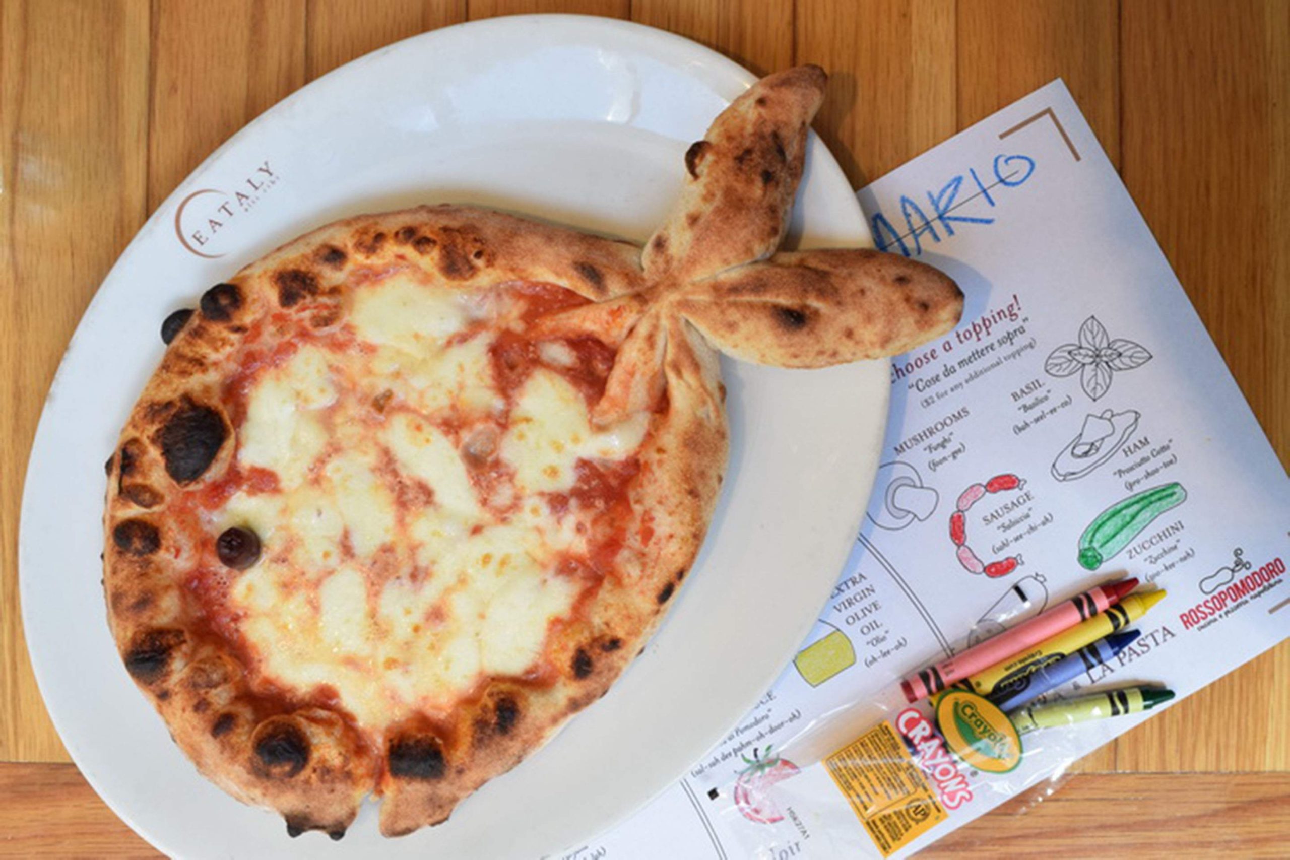 A pizza shaped like a fish next to a coloring book and crayons