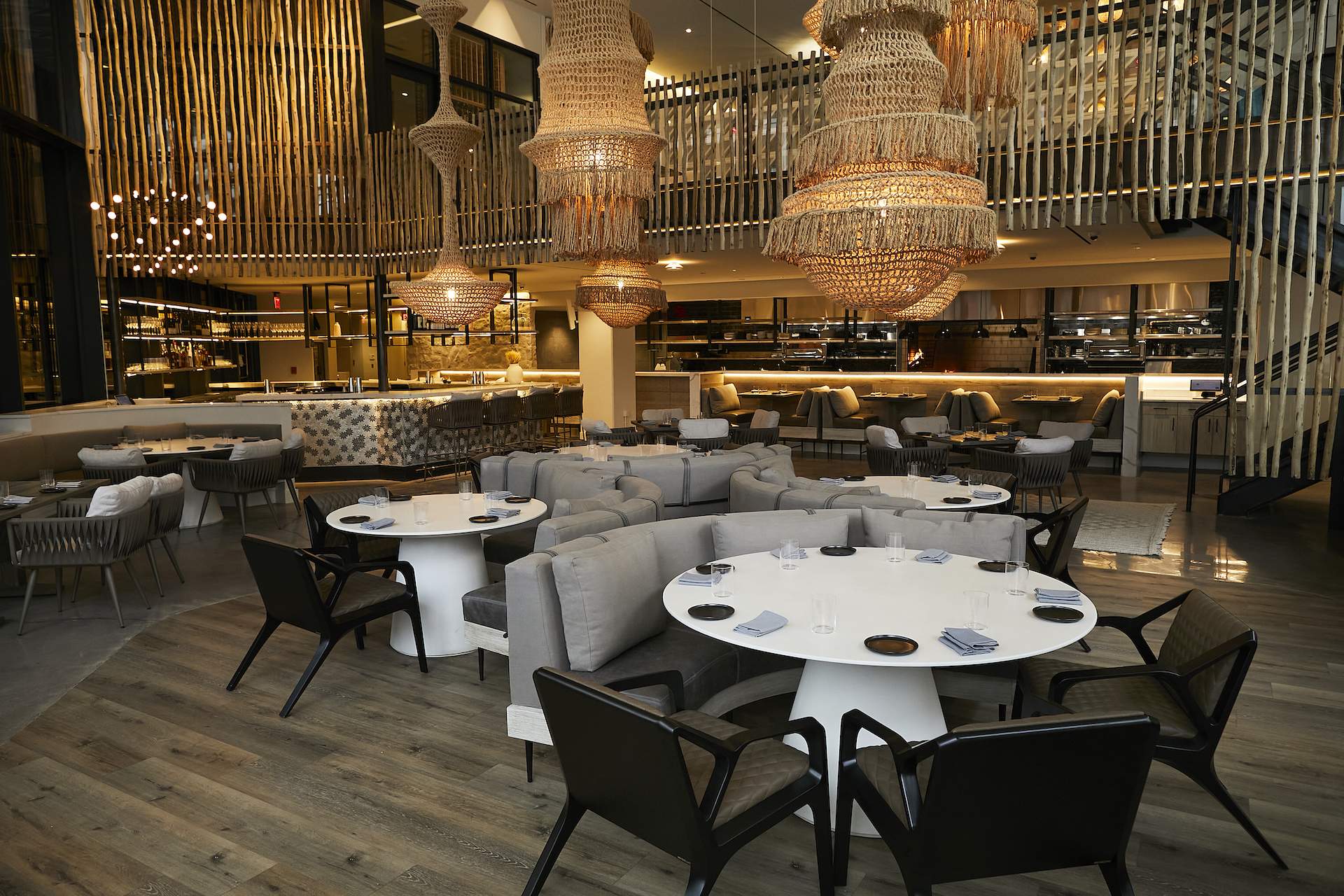The interior of the Washington DC Greek restaurant Philotimo with large chandeliers and white tables with wooden chairs