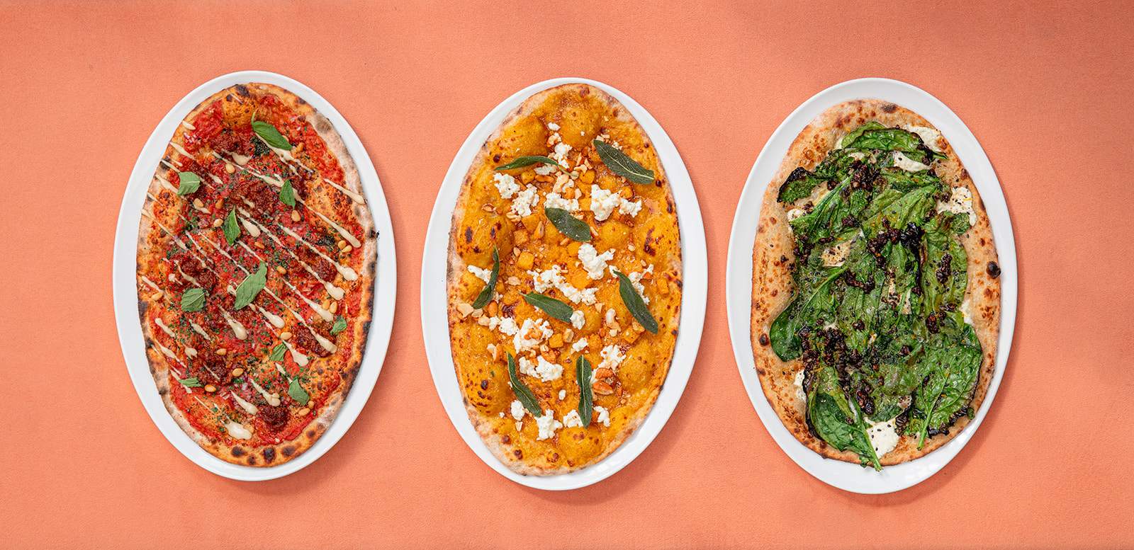 Three flatbreads with toppings including spicy lamb and pork sausage, tomato, red onion, pine nuts, nigella seed, mint, sumac, and sesame paste at Bavel in Los Angeles