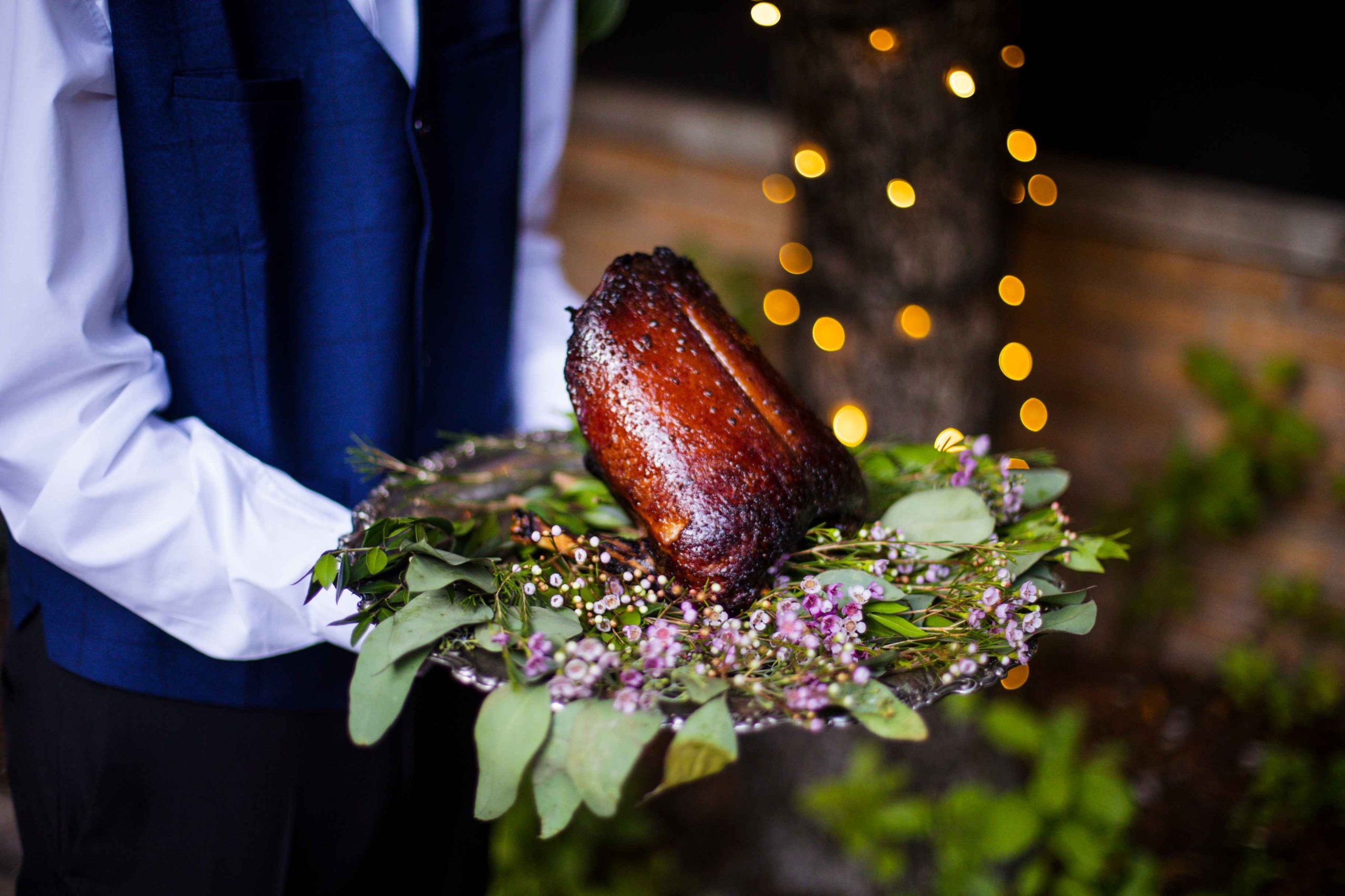 A server presents a whole roasted dry-aged duck wreathed by leaves and purple flowers at Boka in Chicago.