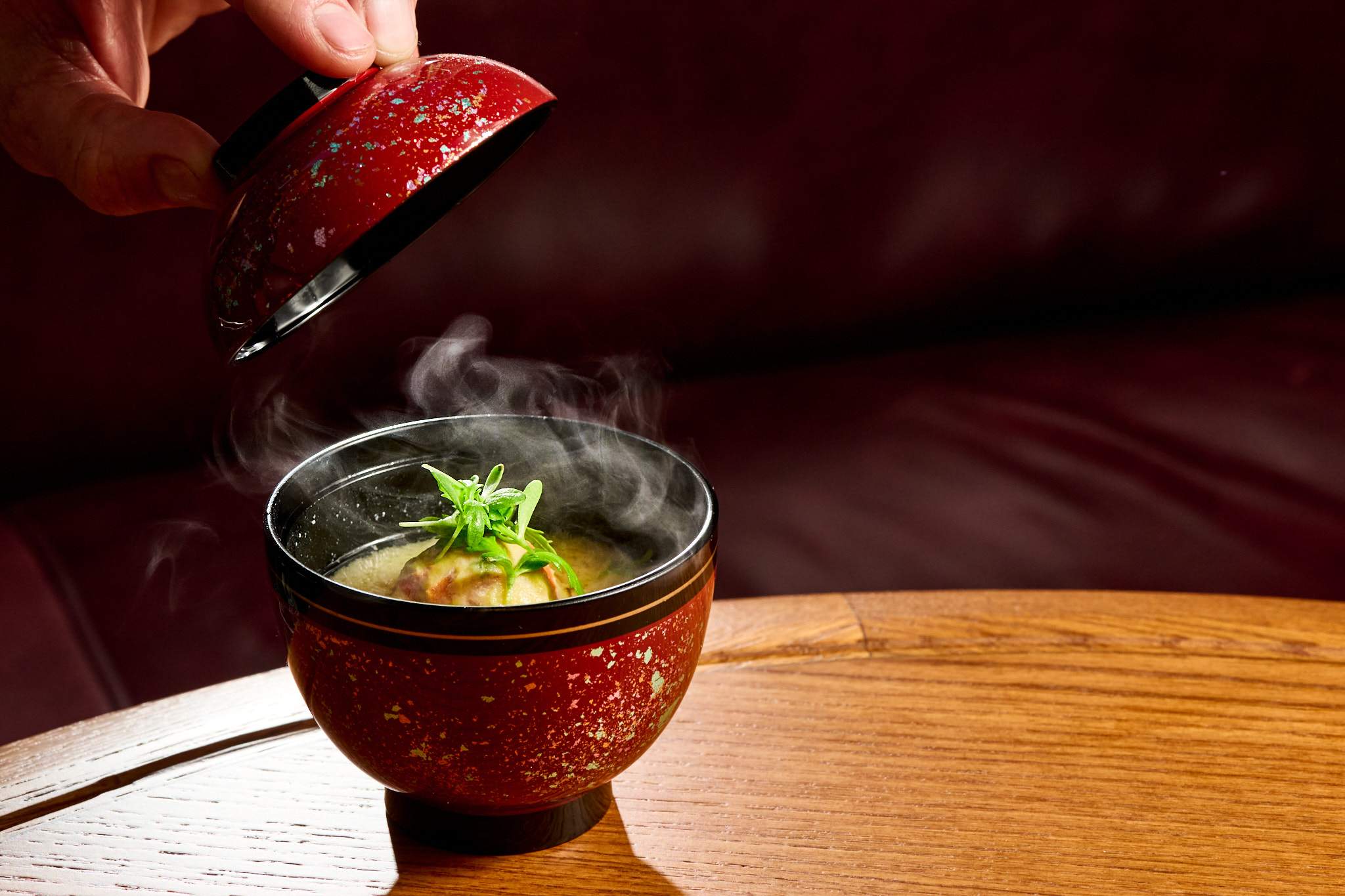 A red lacquer bowl with fish dumplings and miso broth at AKIKOS in San Francisco