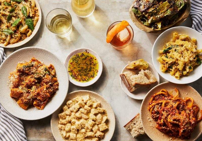A table topped with housemade gnocchi, assorted pastas, and cocktails at MIDA - South End in Boston