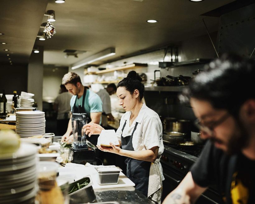 Three cooks work on the line in a restaurant. The industry is trying to find innovative ways to survive.