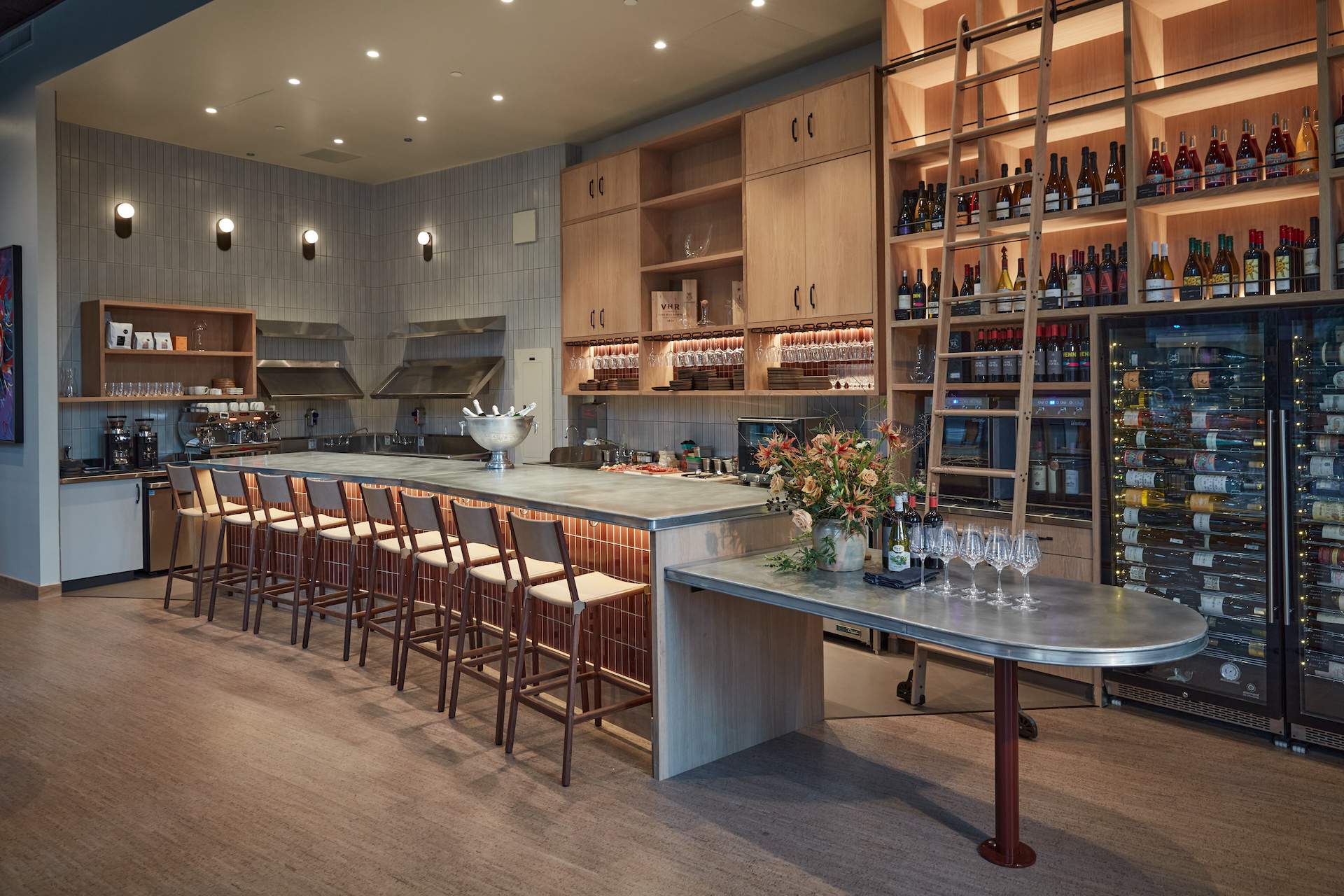 The interior of San Francisco wine bar Mili with light wood finishes and a slate bar counter with chairs up against it.