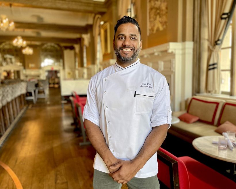 Boston chef Zaid Khan in a white apron and green trousers at his restaurant Oak Long Bar + Kitchen