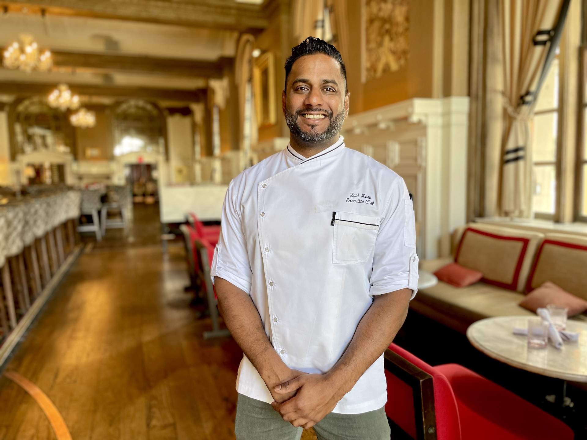 Boston chef Zaid Khan in a white apron and green trousers at his restaurant Oak Long Bar + Kitchen