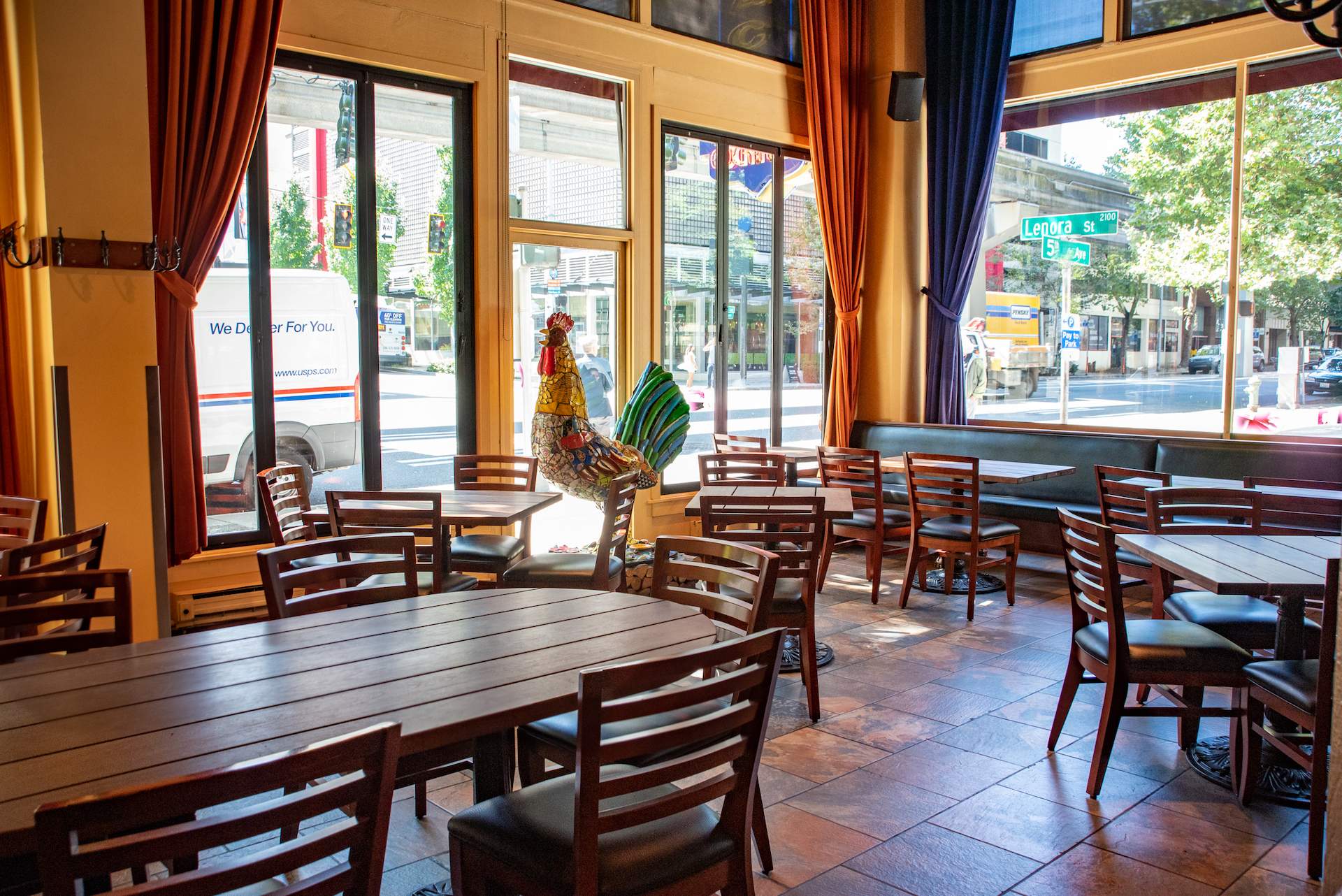 The interior of Seattle restaurant Palace Kitchen seen here with floor-to-ceiling windows and wooden tables and chairs.