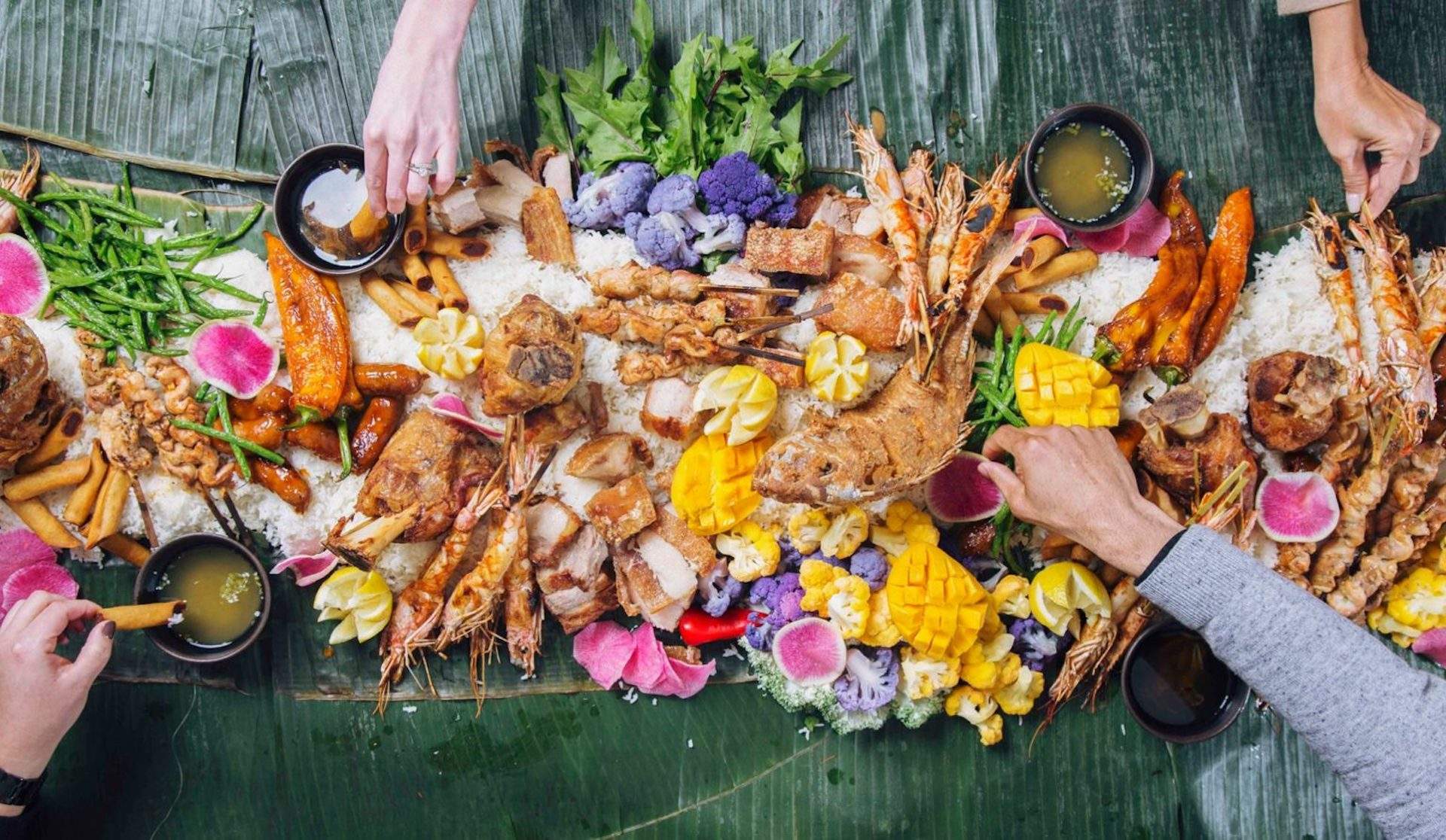 A colorful array of food on banana leaves called at a Kamayan feast at Chicago Filipino restaurant Sunda