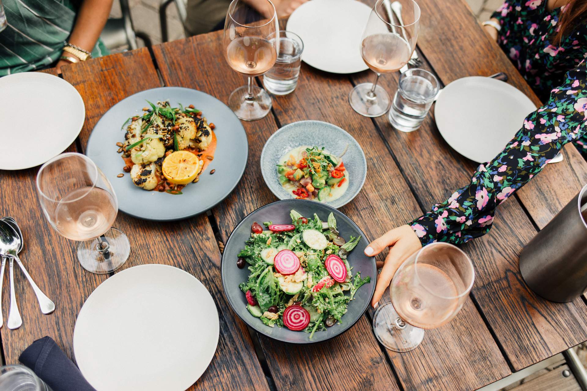 Wine glasses and plates of food on a wooden table at Chicago restaurant the Dawson.