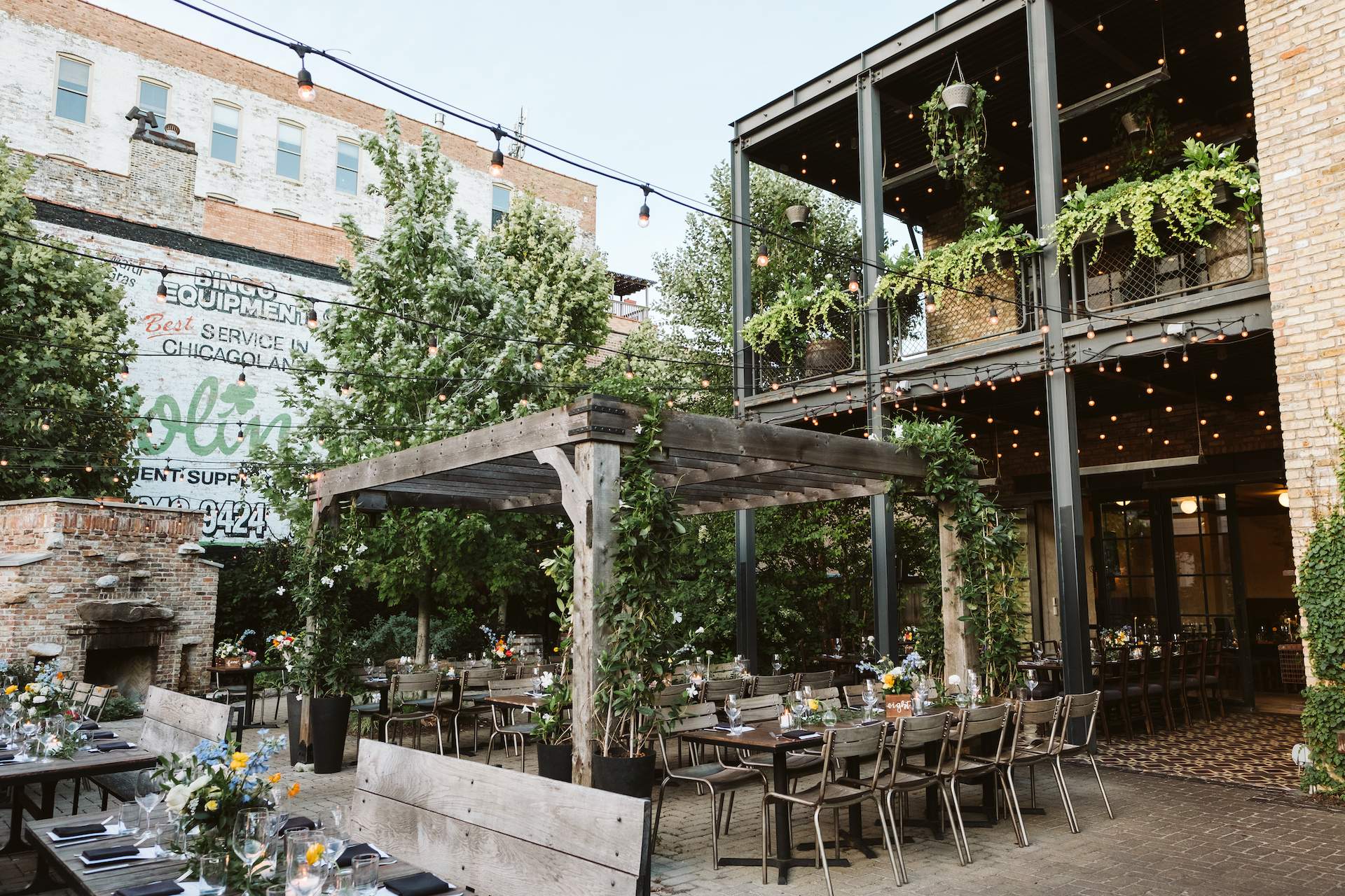 The patio of the Chicago restaurant the Dawson that can be seen full of trees and a wooden structure in the center.