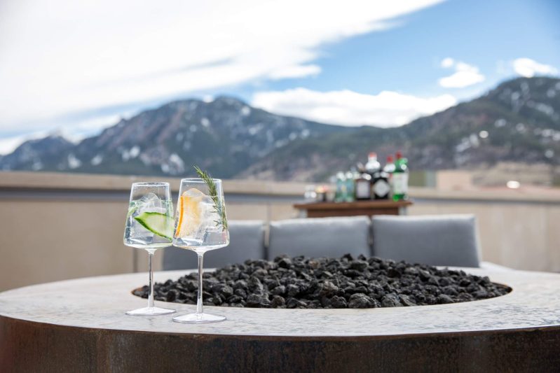 A pair of gin and tonics by a fire pit at Corrida in Boulder, with Flatiron mountain views in the distance