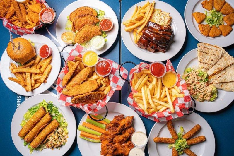 Various fried foods including chicken wings, mozzarella sticks, and nuggets placed next to each other on a table at Washington DC bar Nellie’s.