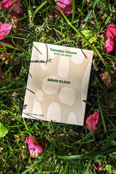 A box of cannabis gummies against a backdrop of grass and rose petals.