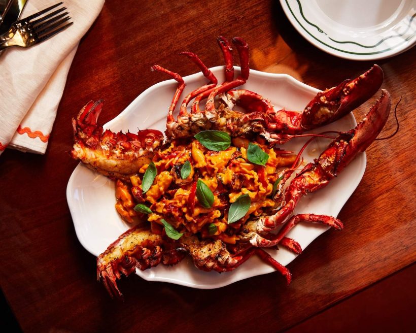 A crab split in the middle with pasta and basil leaves at NYC restaurant Bad Roman