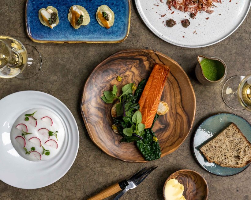 New Zealand-inspired seafood and two glasses of white wine top a table at Quarter Acre in Dallas
