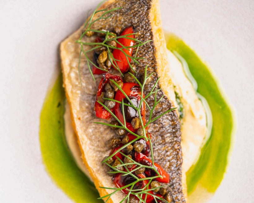 A close up of a fish dish with roasted tomatoes at NYC restaurant Gotham.