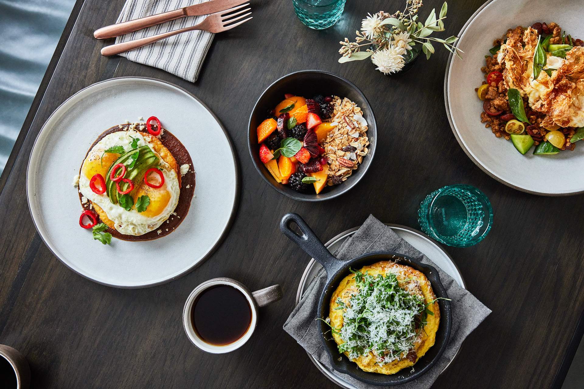 Several plates of food including an omelet in a cast-iron skillet placed on a wooden table at Los Olivos restaurant Mattei’s Tavern.