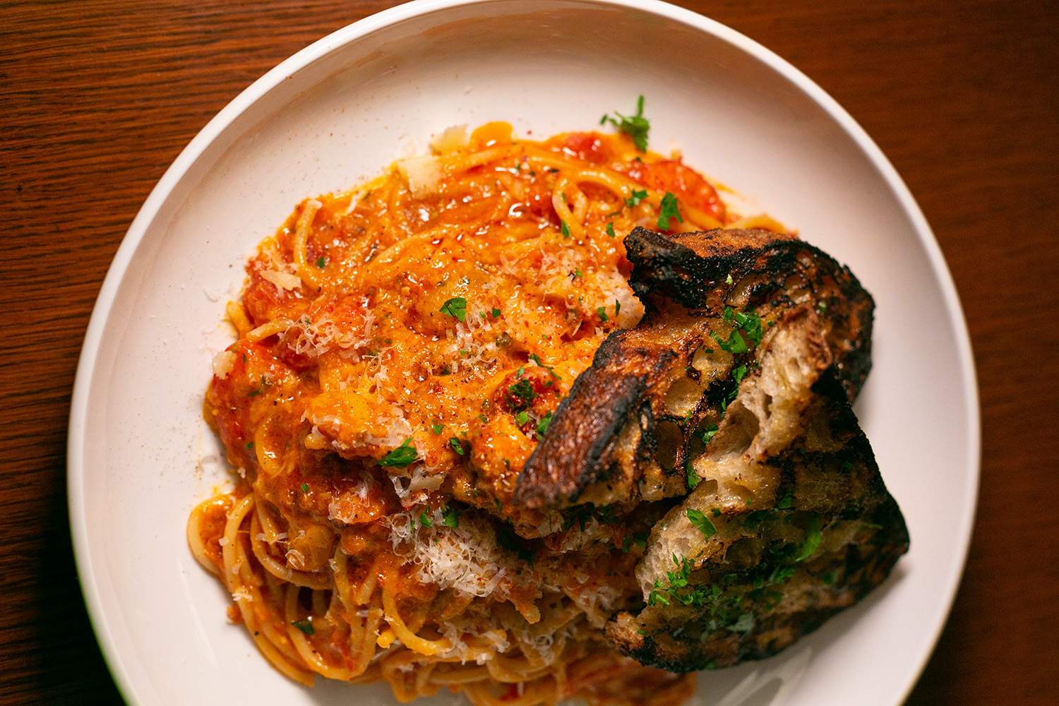 An orange spaghetti dish with lobster and toasted bread at Los Angeles restaurant Saltie Girl.