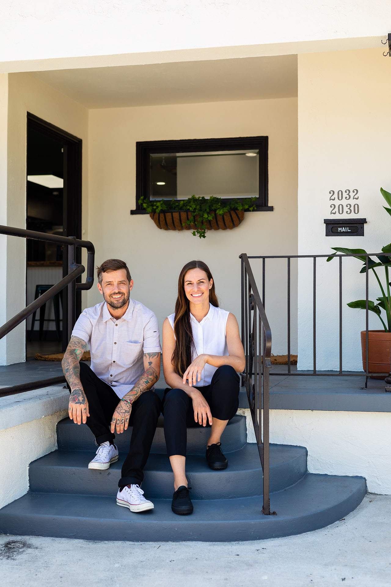 A man and woman sit side by side on the steps of a restaurant.