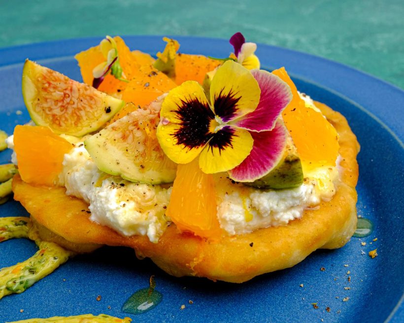 A fried piece of bread called yaniqueque topped with ricotta cheese and fruits at a new NYC pop-up called Dōekï Dōekï from chef Paola Velez.