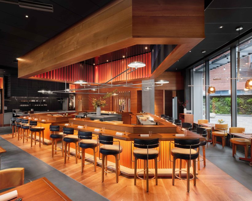 AKIKOS in San Francisco spans 2,700 square feet with a chef’s wooden counter at the center, illuminated in golden light.