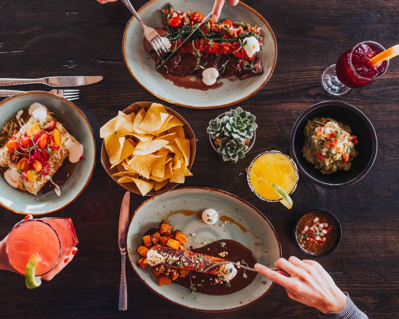 An array of modern Mexican dishes including chicken tinga enchiladas, guacamole, and colorful cocktails at Tamayo Restaurant in Denver