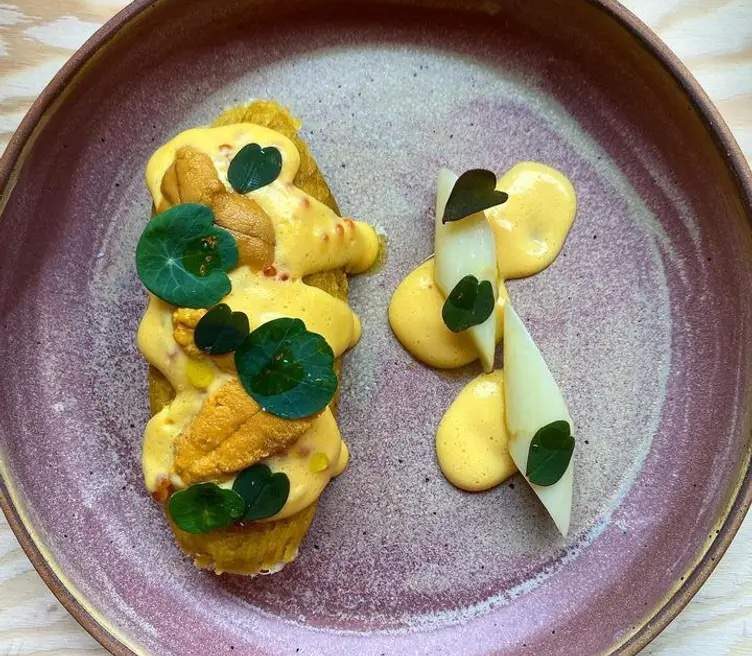 A composed plate of fish and yellow pastes at Portland restaurant Lilia Comedor