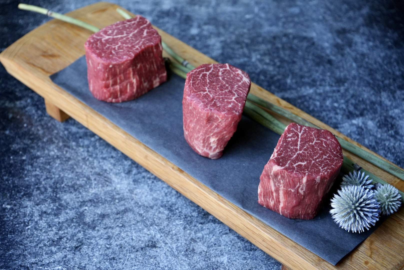 Three slabs of wagyu on a rectangular wooden tray at Niku Steakhouse in San Francisco