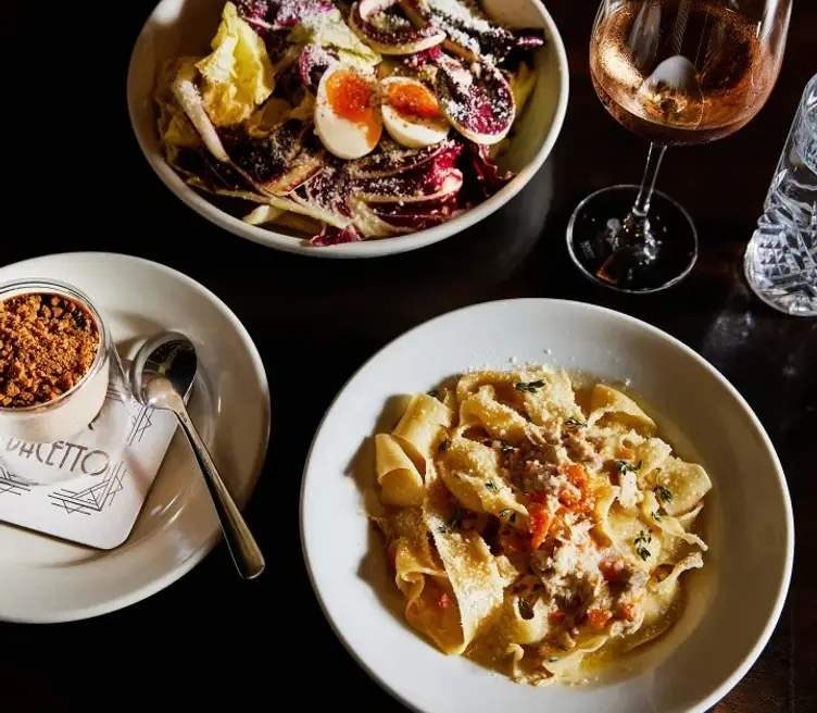 Four dishes and a glass of wine placed on a table at Waitsburg restaurant Bar Bacetto