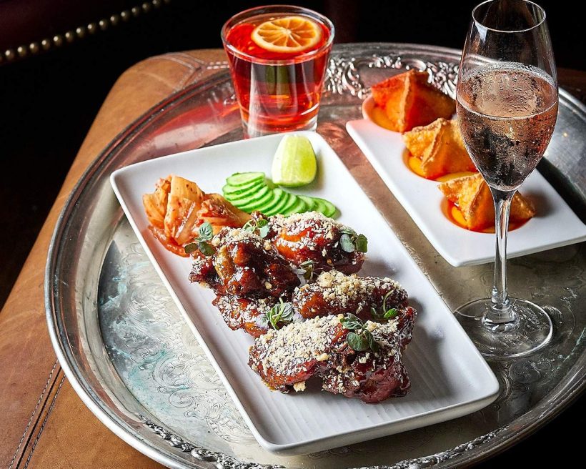 A negroni, a glass of sparkling wine, and various appetizers on a silver tray at Curio in San Francisco