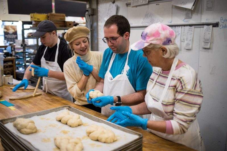 Four people place mounds of kneaded dough on a kitchen counter at Soul Cafe in West Bloomfield, Michigan